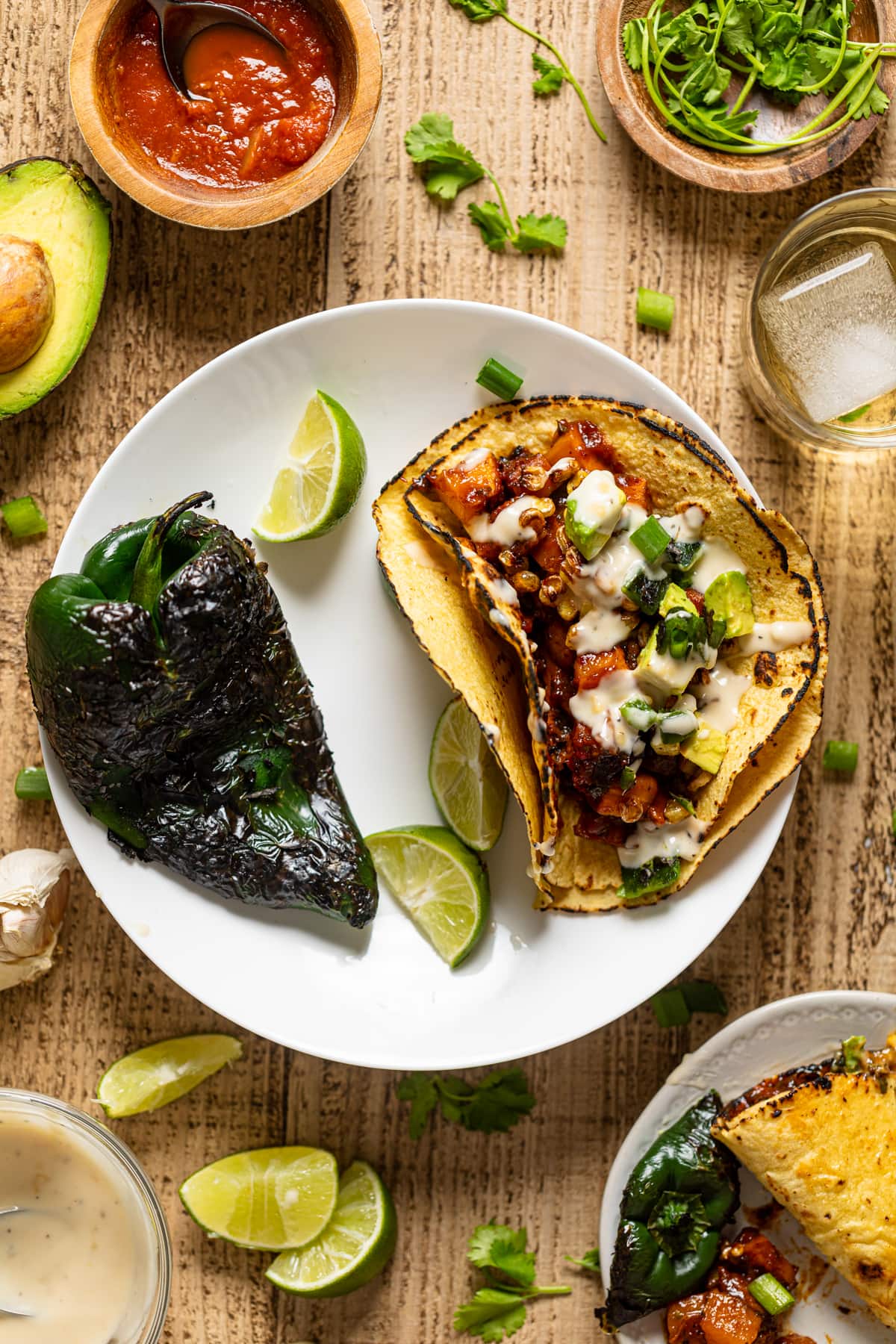 Chipotle barbeque Butternut Squash Taco on a plate with a charred pepper and lime wedges