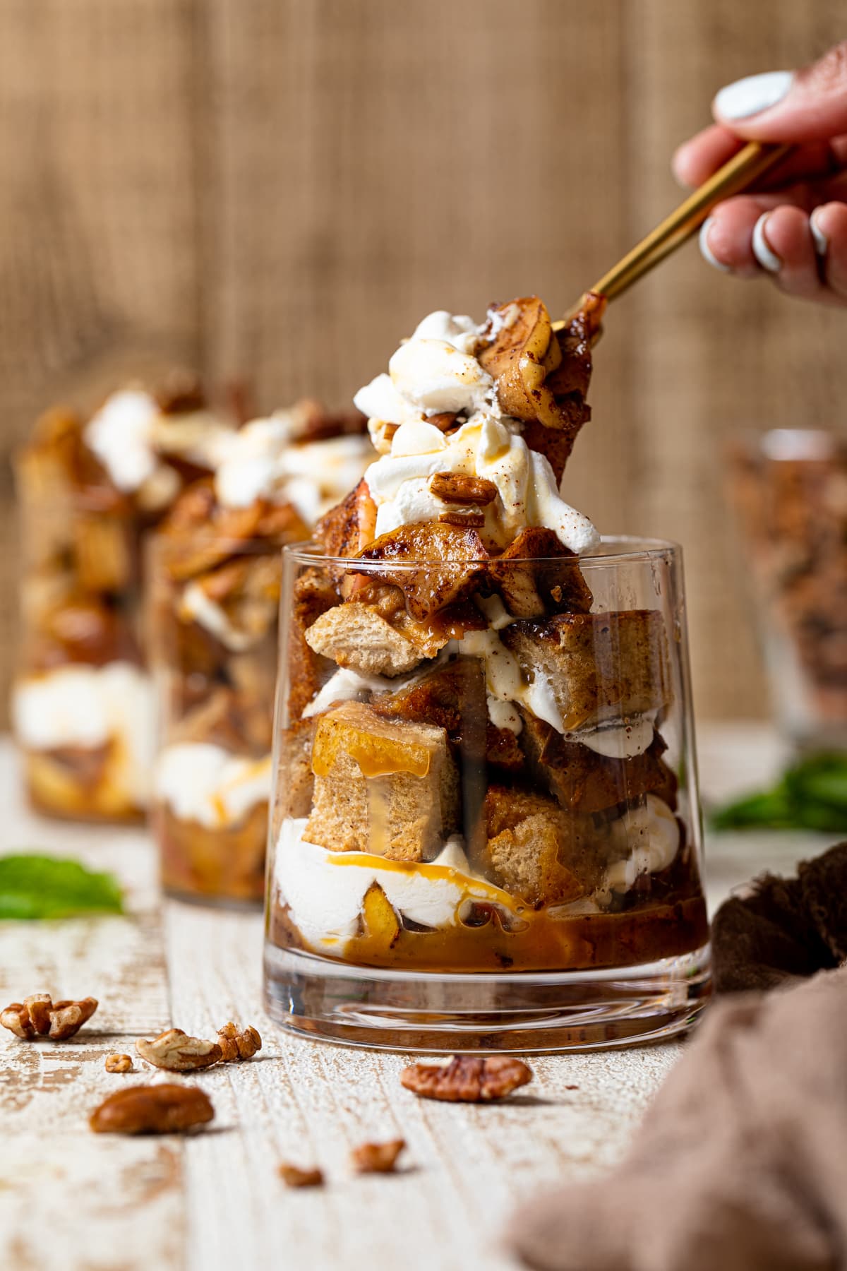 Hand using a fork to grab some Caramel Apple French Toast Parfait out of a glass