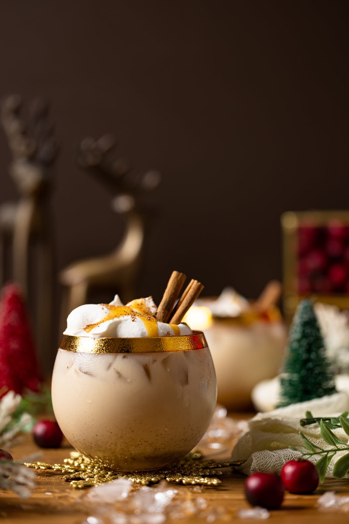 Vegan Caramel Eggnog Mocktail topped with coconut whipped cream, cinnamon sticks, and caramel sauce