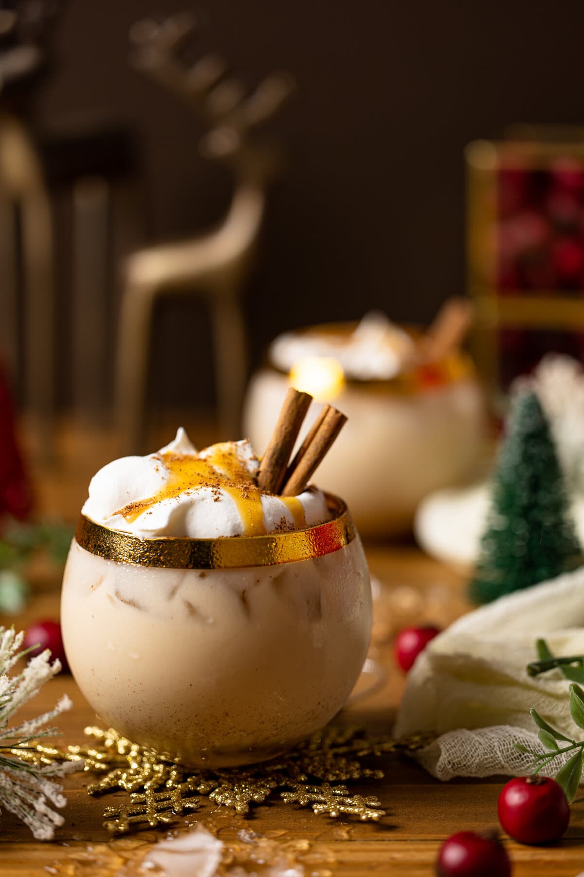 Vegan Caramel Eggnog Mocktail topped with coconut whipped cream, cinnamon sticks, and caramel sauce