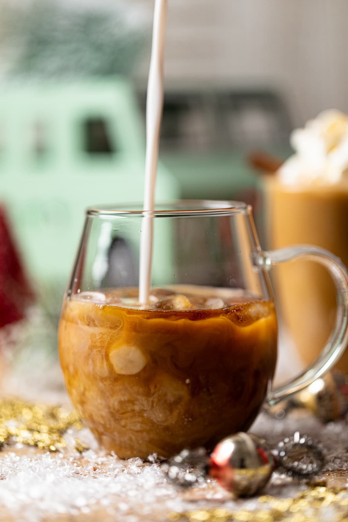 Oat milk pouring into a glass mug to make an Iced Maple Cinnamon Oat Latte