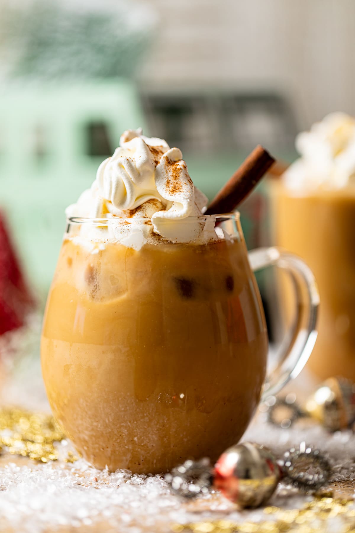 Iced Maple Cinnamon Oat Latte topped with coconut whipped cream and cinnamon sticks