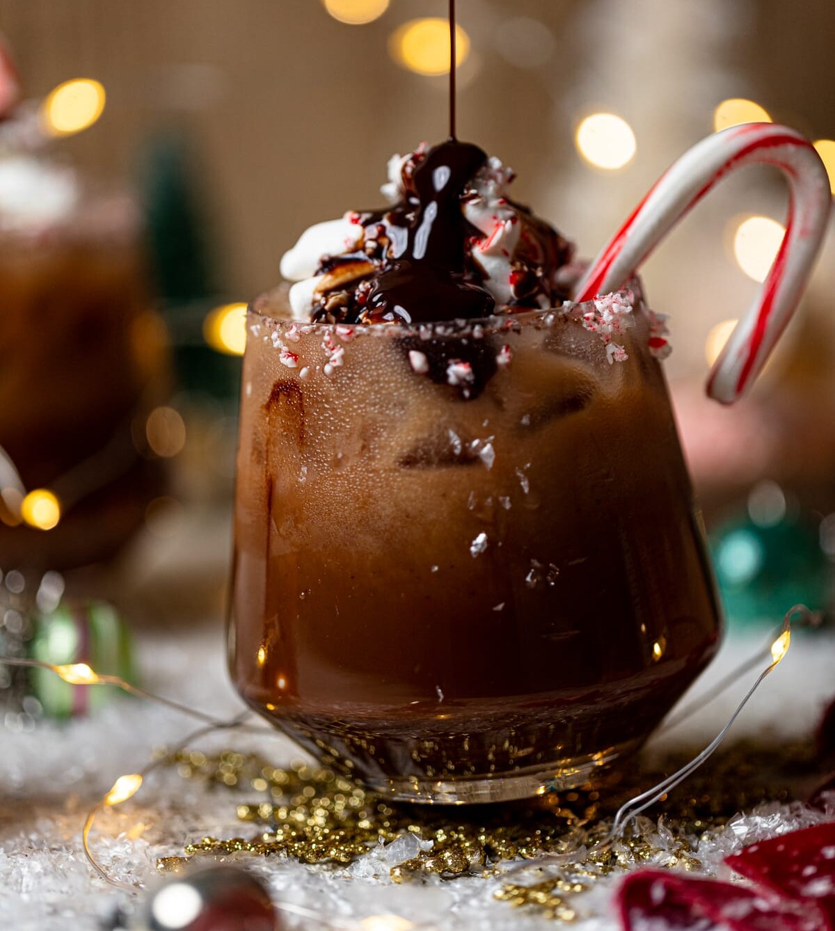 Chocolate syrup pouring onto a Chocolate Christmas Mocktail with a candy cane