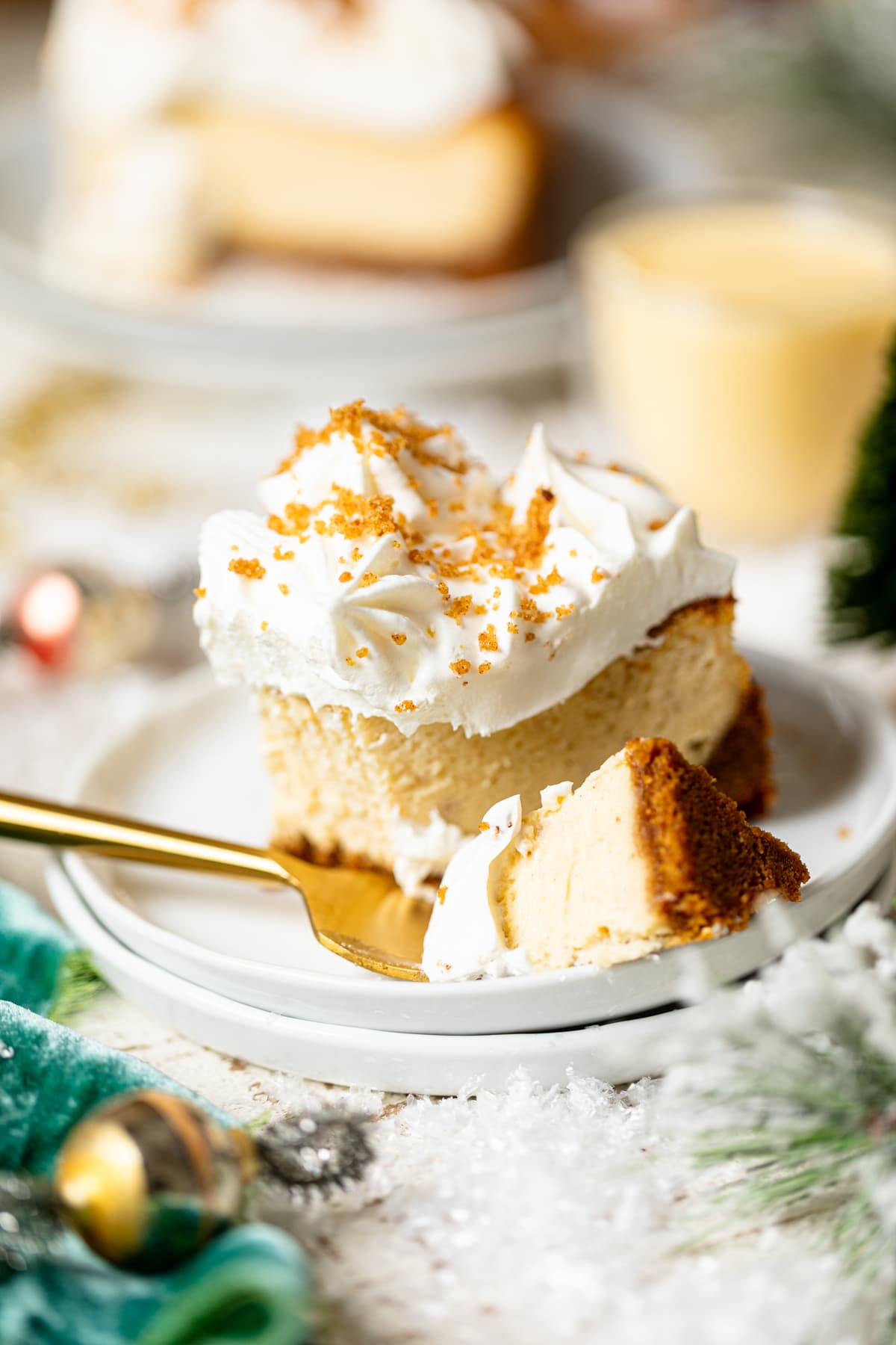 Slice of Eggnog Cheesecake with Snickerdoodle Crust on two small, stacked plates with a fork