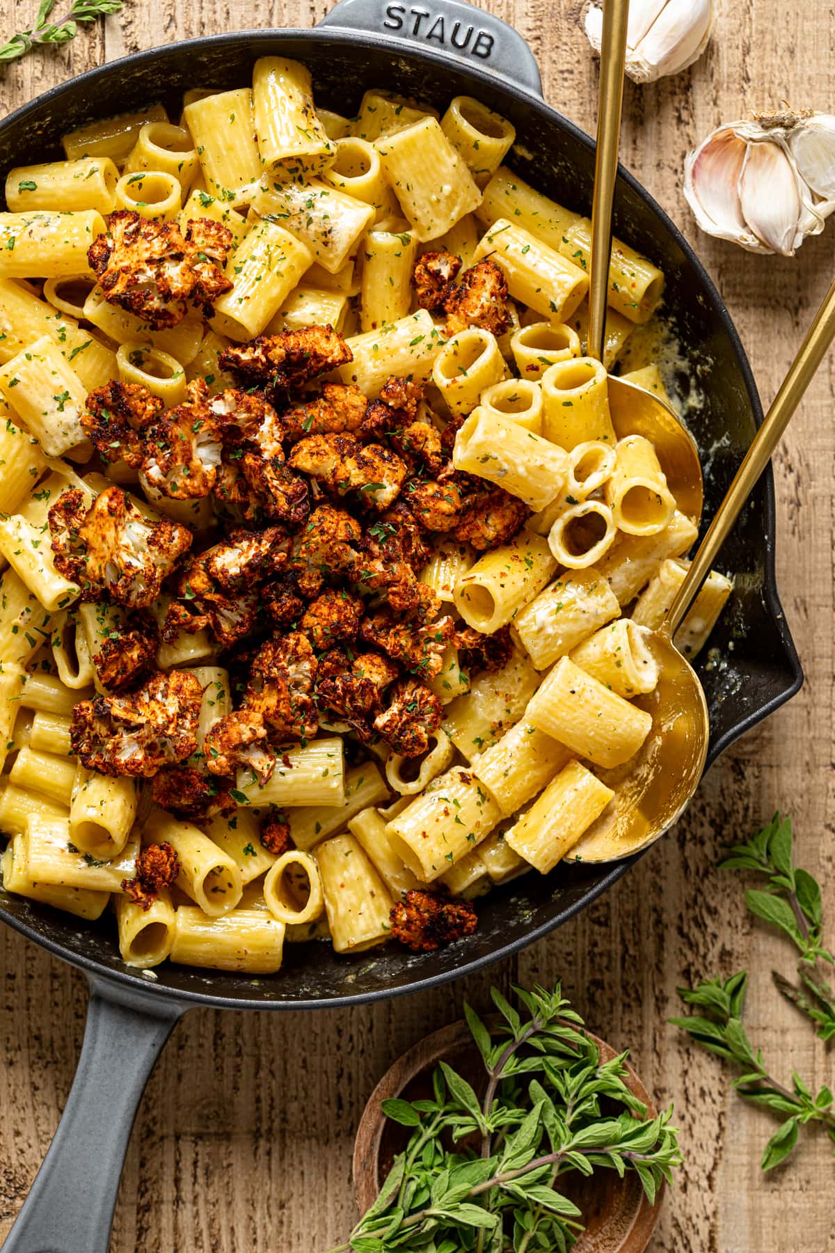 Two serving spoons in a skillet of Creamy Garlic Butter Pasta with Roasted cauliflower