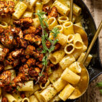 Closeup of two serving spoons in a skillet of Creamy Garlic Butter Pasta with Roasted cauliflower