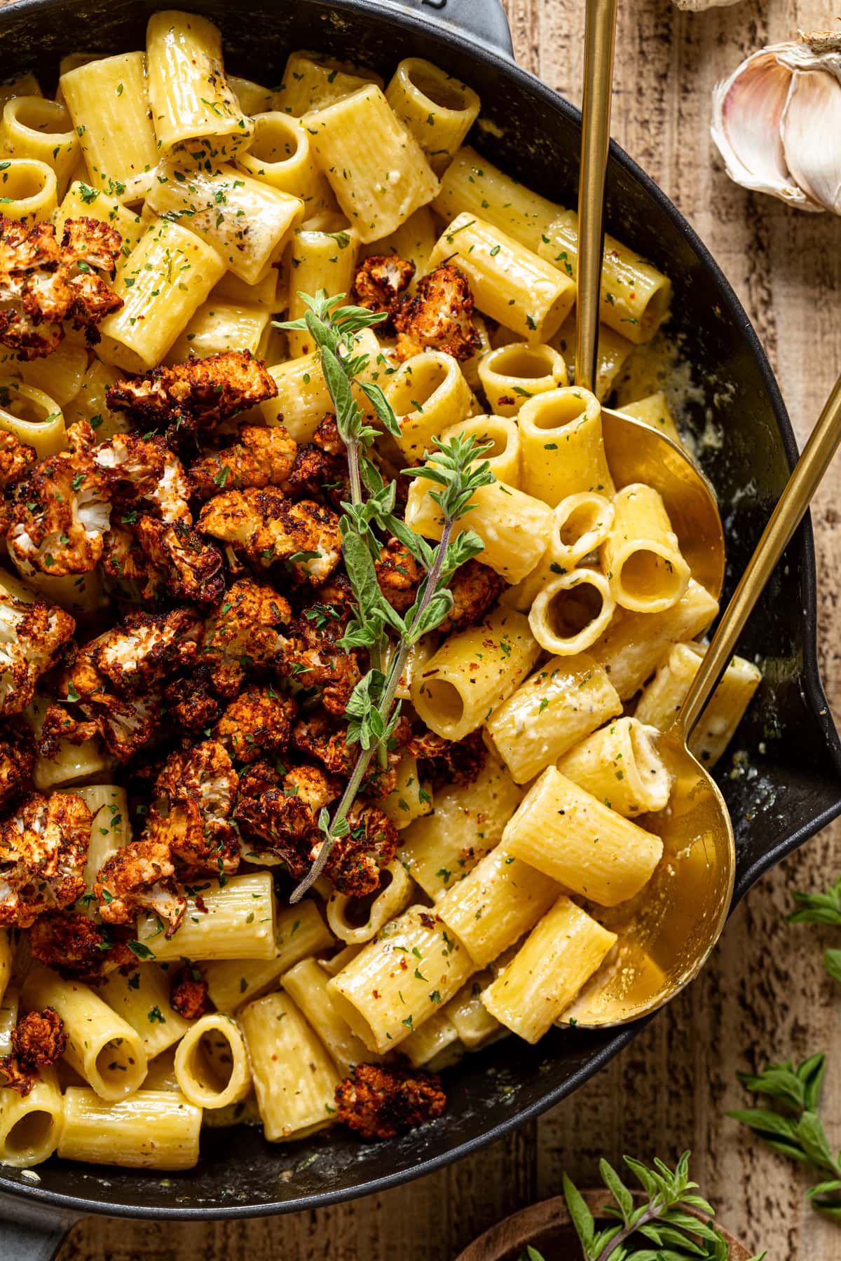 Closeup of two serving spoons in a skillet of Creamy Garlic Butter Pasta with Roasted cauliflower