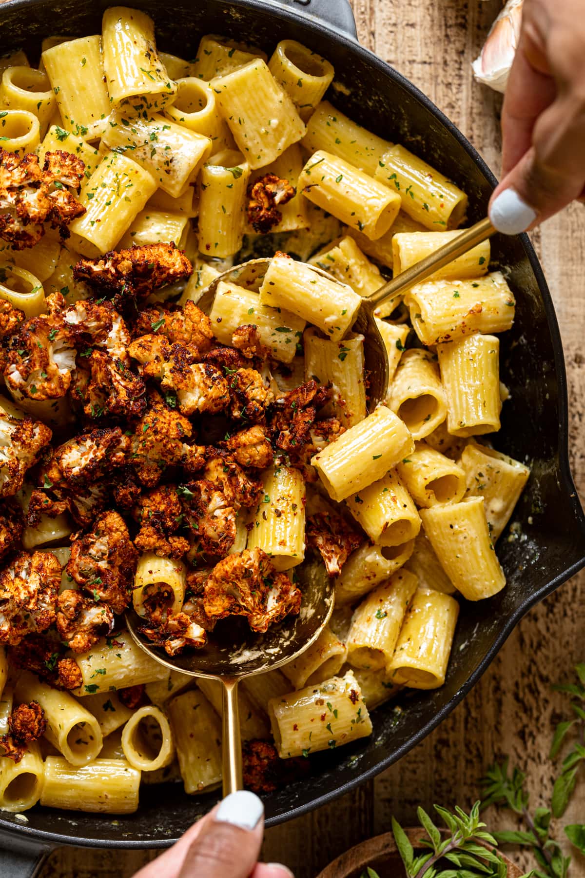 Closeup of two serving spoons in a skillet of Creamy Garlic Butter Pasta with Roasted cauliflower