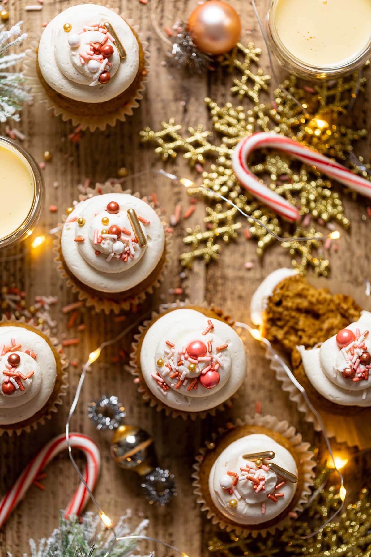 Gingerbread Cupcakes with Eggnog Frosting on a table with Christmas decorations including gold-colored snowflakes