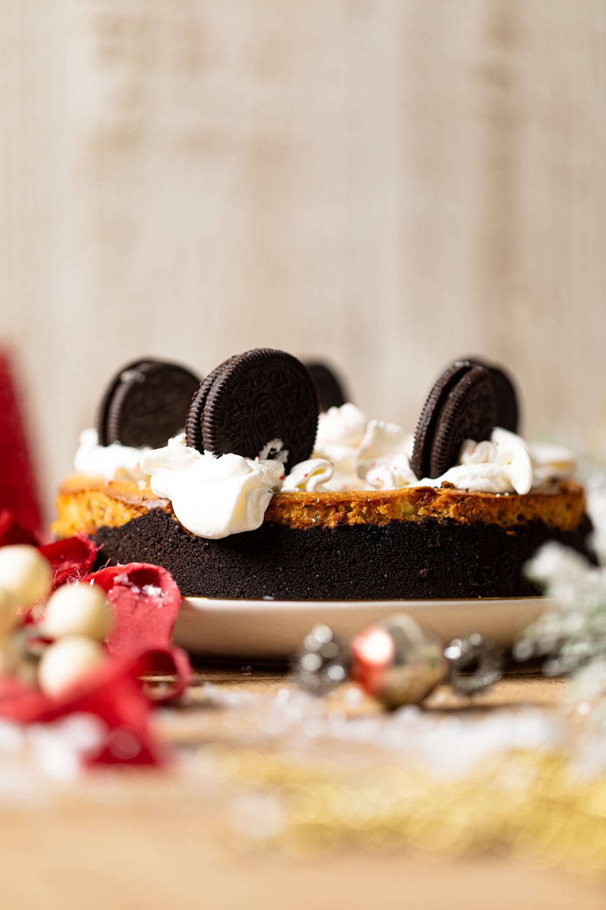 Peppermint Oreo Cheesecake on a plate surrounded by Christmas decorations