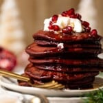 Stack of Fluffy Red Velvet Pancakes topped with whipped cream and pomegranate seeds