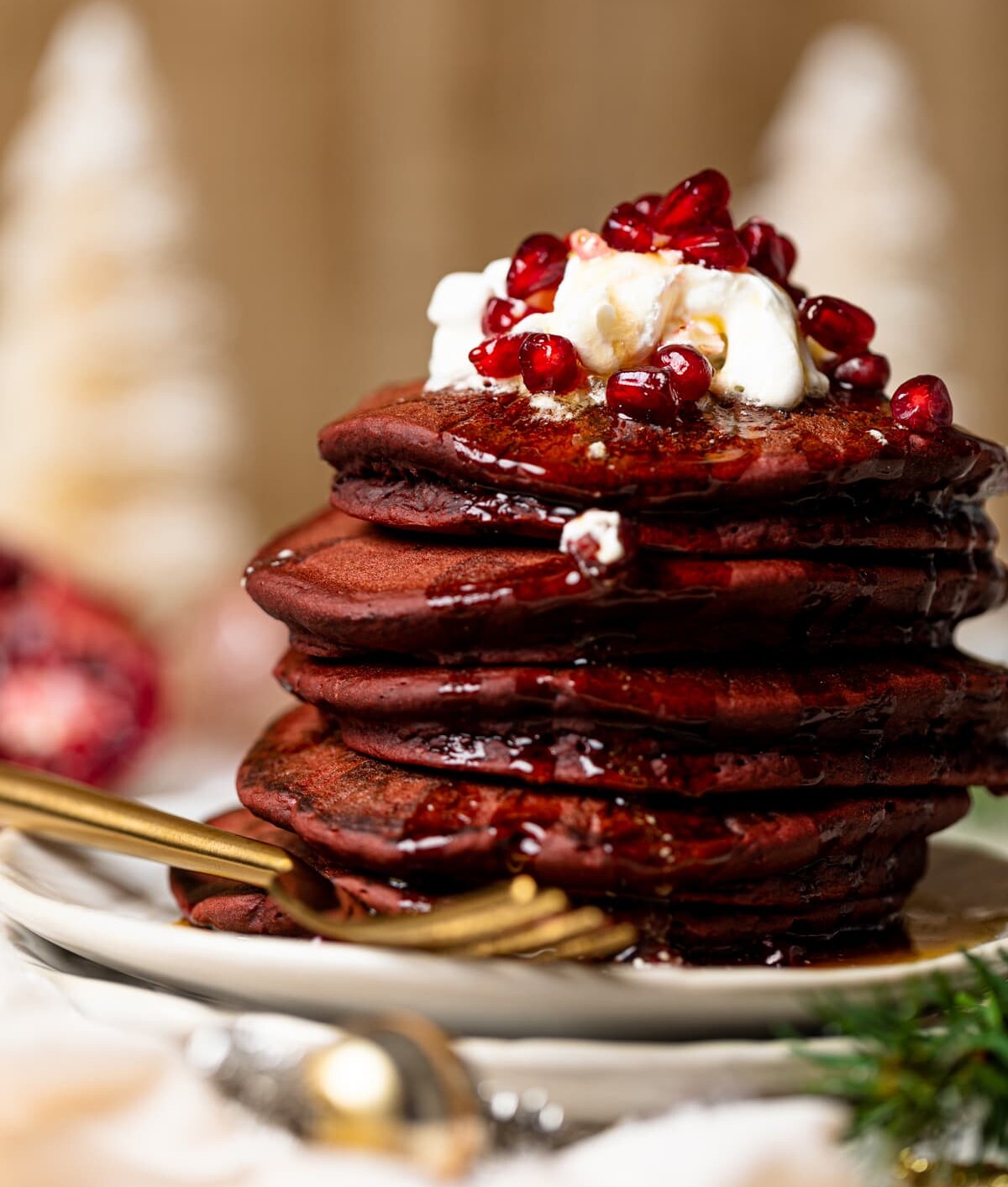 Stack of Fluffy Red Velvet Pancakes topped with whipped cream and pomegranate seeds