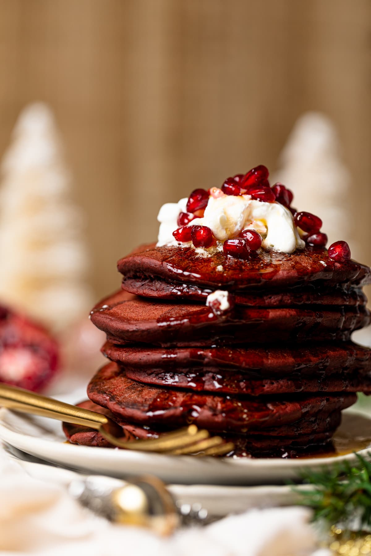 Stack of Fluffy Red Velvet Pancakes topped with whipped cream and pomegranate seeds