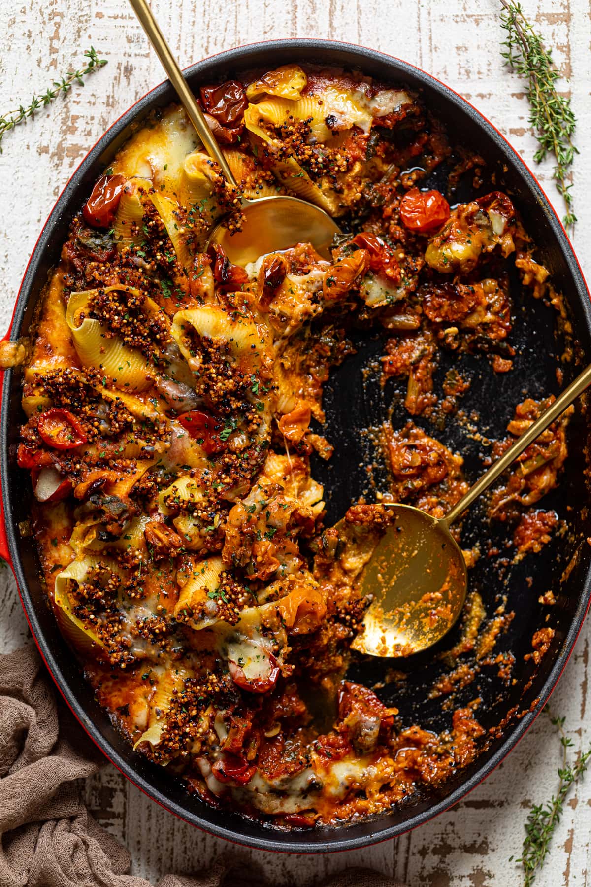 Serving spoon in a partially-served, oblong pan of Butternut Squash Stuffed Shells with Quinoa and Kale