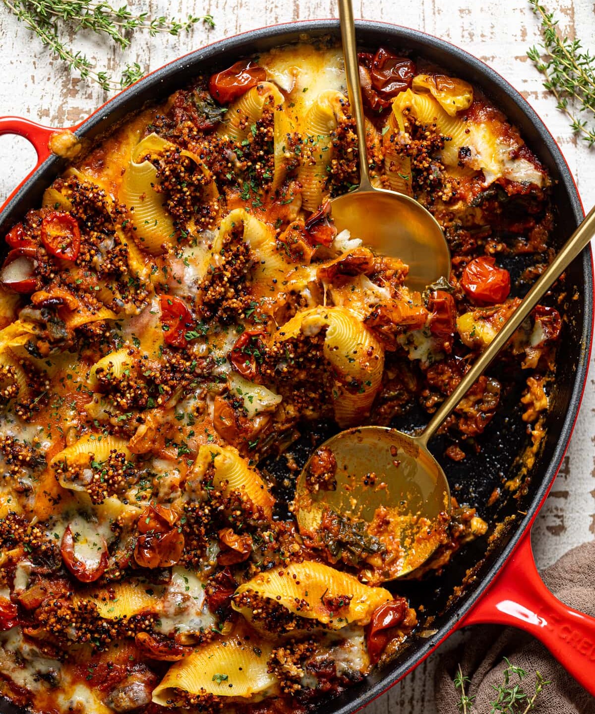 Two serving spoons in an oblong pan of Butternut Squash Stuffed Shells with Quinoa and Kale. Part of the fall pasta recipes roundup. 