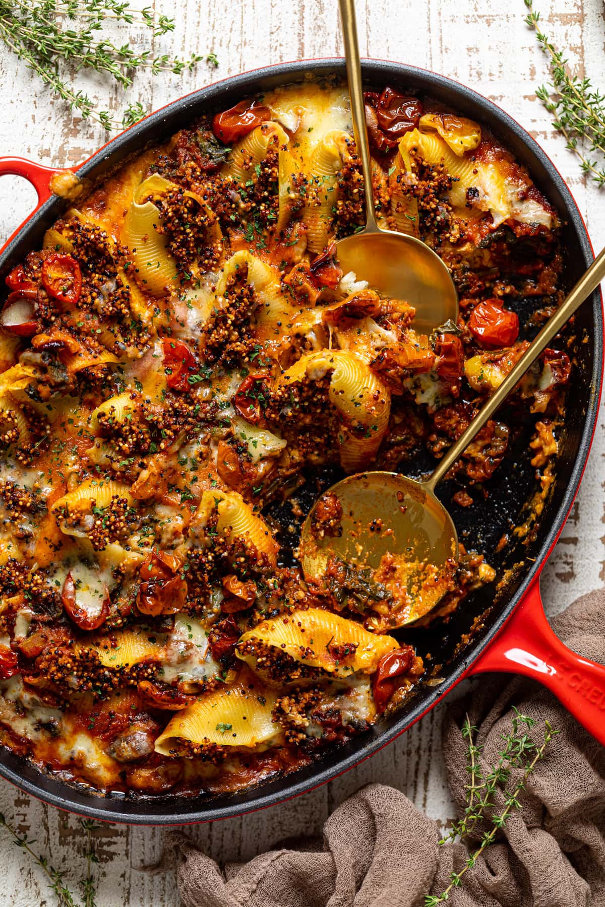 Two serving spoons in an oblong pan of Butternut Squash Stuffed Shells with Quinoa and Kale