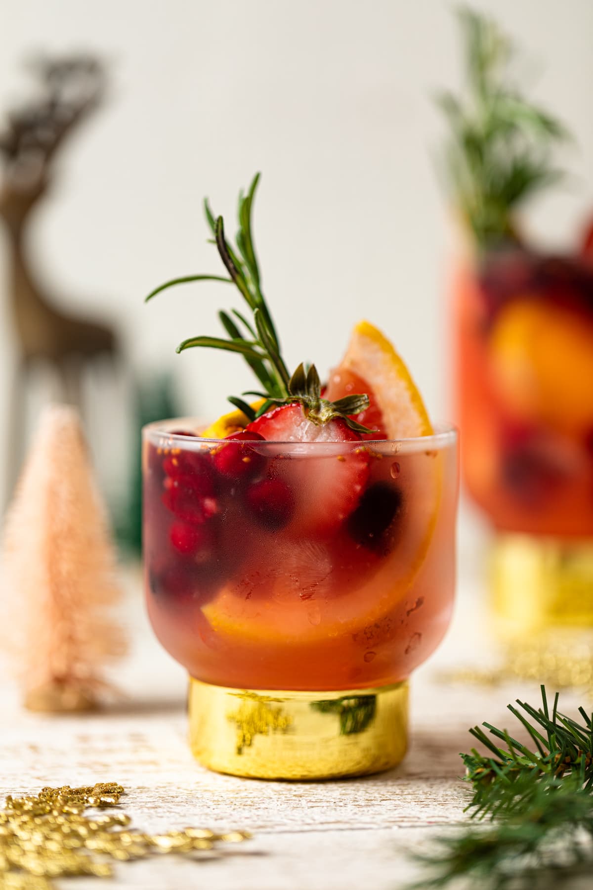 Holiday Mocktail stuffed with cranberries, strawberries, rosemary, and blood orange