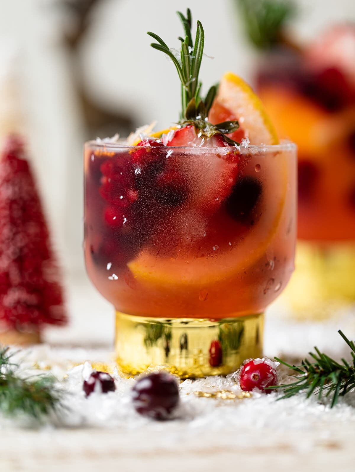 Holiday Mocktail stuffed with cranberries, strawberries, rosemary, and blood orange