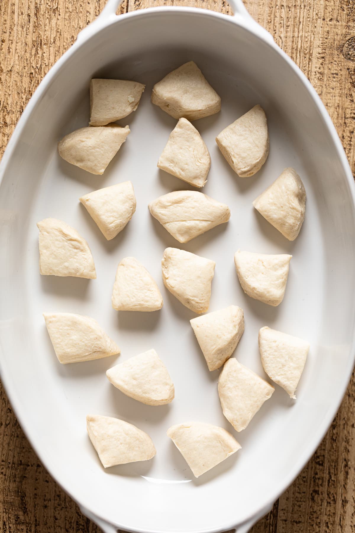 Pieces of biscuit dough on the bottom of a baking dish