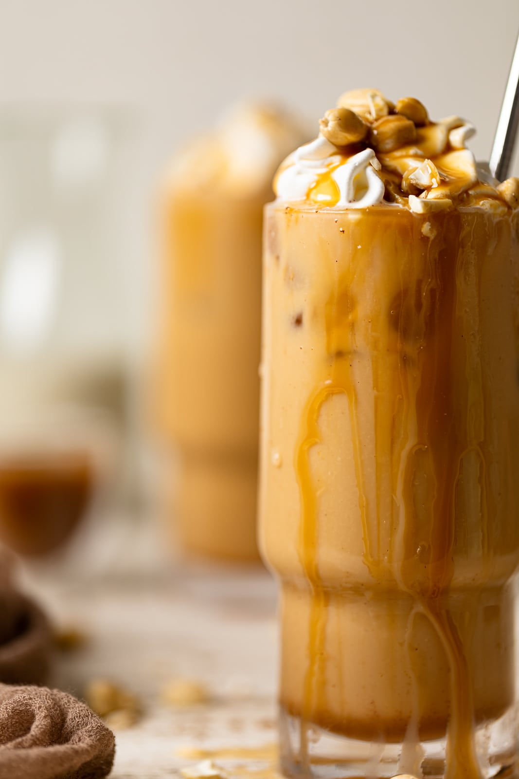Closeup of a Salted Caramel Cashew Latte in a tall glass with caramel dripping down the side