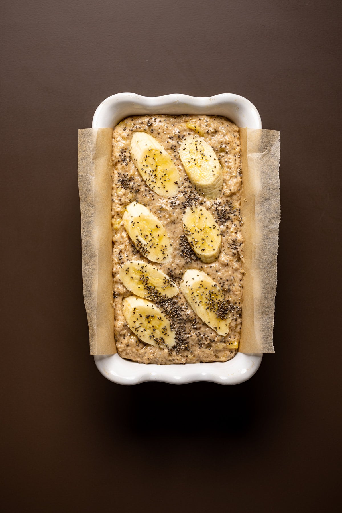 Vegan Chia Seed Maple Banana Bread batter topped with banana slices and chia seeds in a bread pan