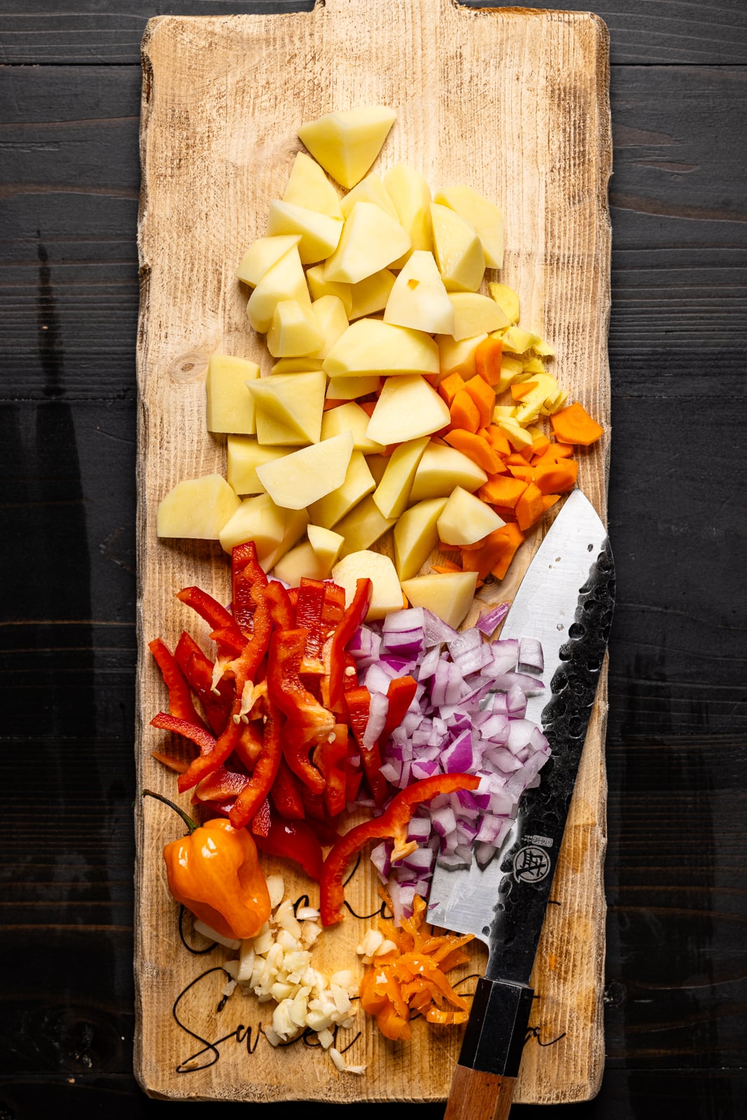 Chopped veggies on a cutting board with a knife.