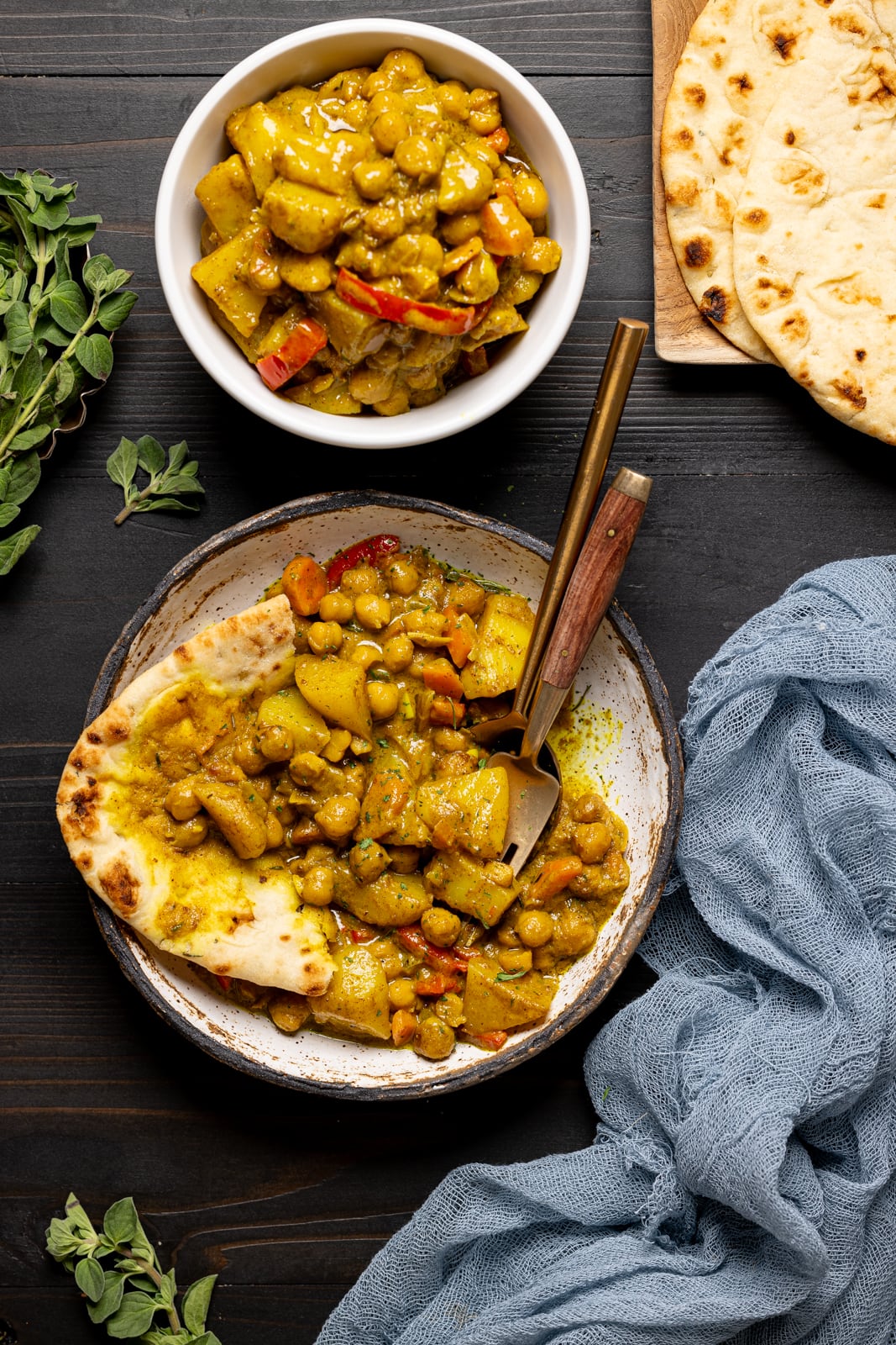 Two bowls of curry with a side of naan bread.