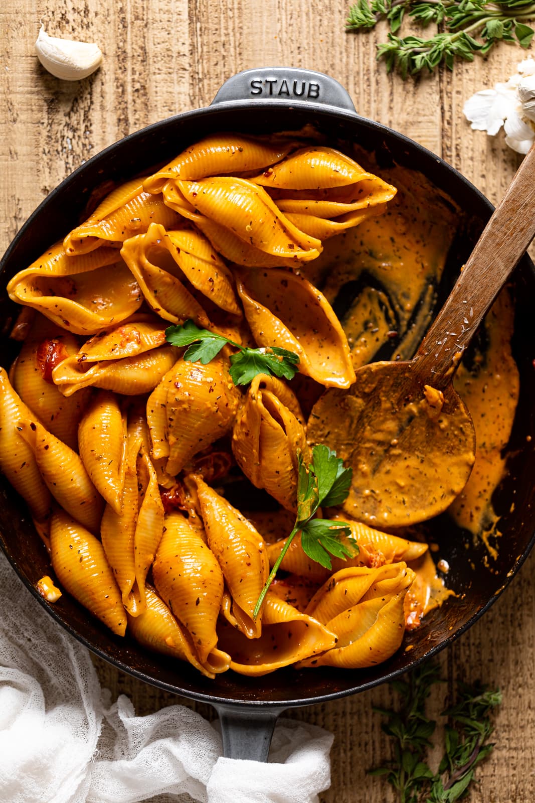 Wooden spoon in a half-served skillet of Creamy Garlic Tomato Jumbo Shell  Pasta