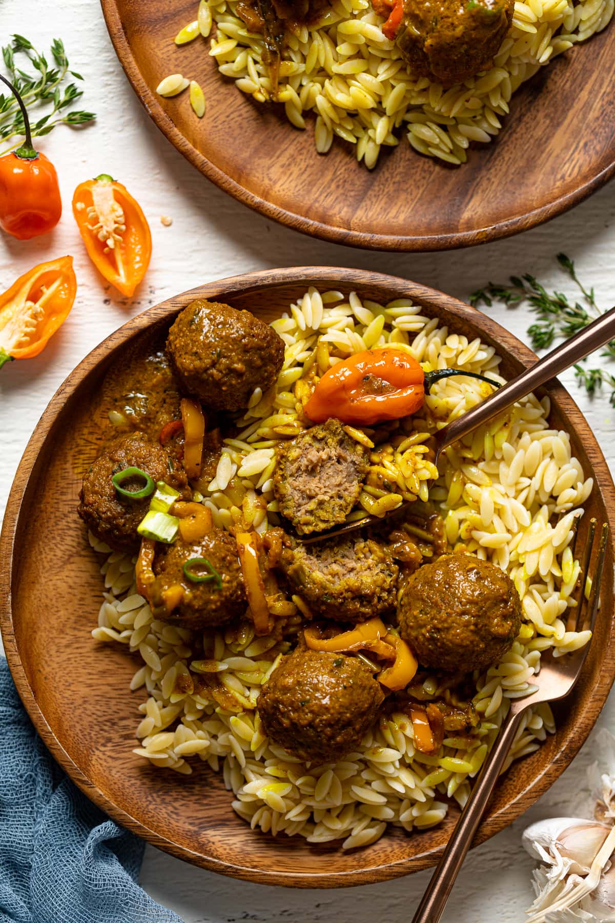 Closeup of a wooden plate of Spicy Curry Vegan Meatballs with Orzo