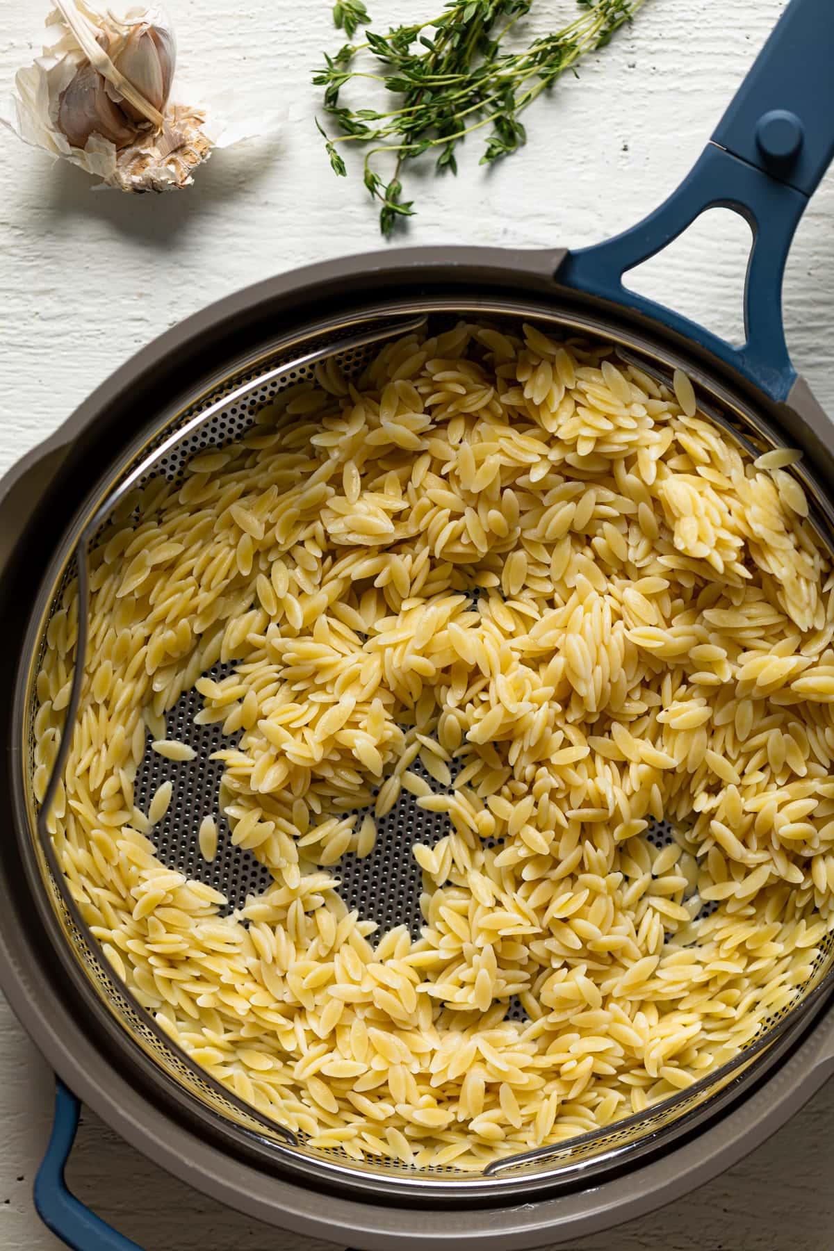 Orzo in a strainer over a pot