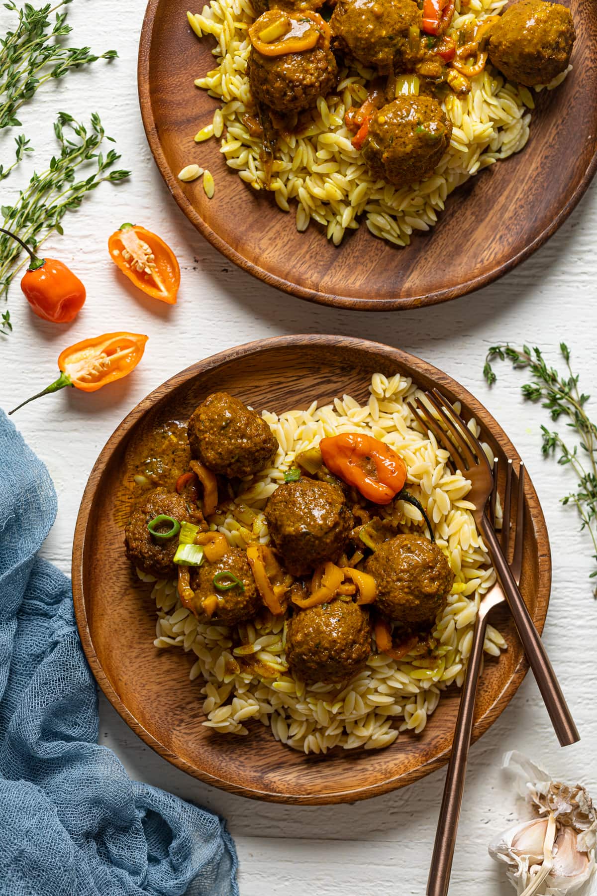 Two wooden plates of Spicy Curry Vegan Meatballs with Orzo