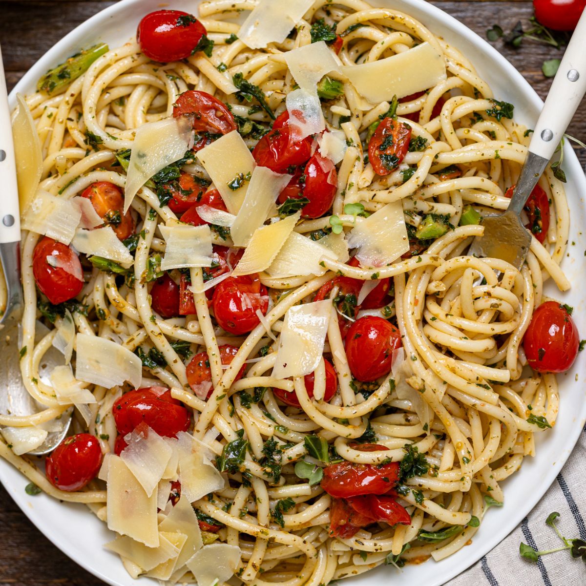 Easy Bruschetta Pasta with Parmesan in a serving platter with. utensils with garnish.