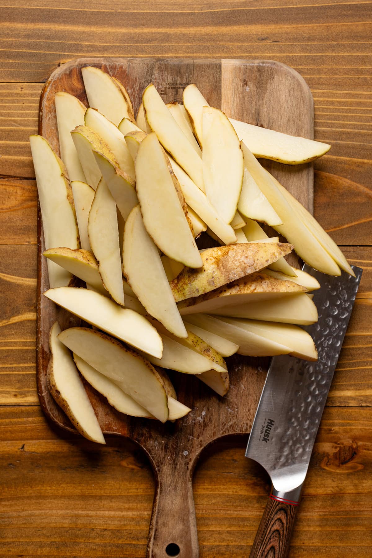 Chopped potatoes on a cutting board with a knife. 