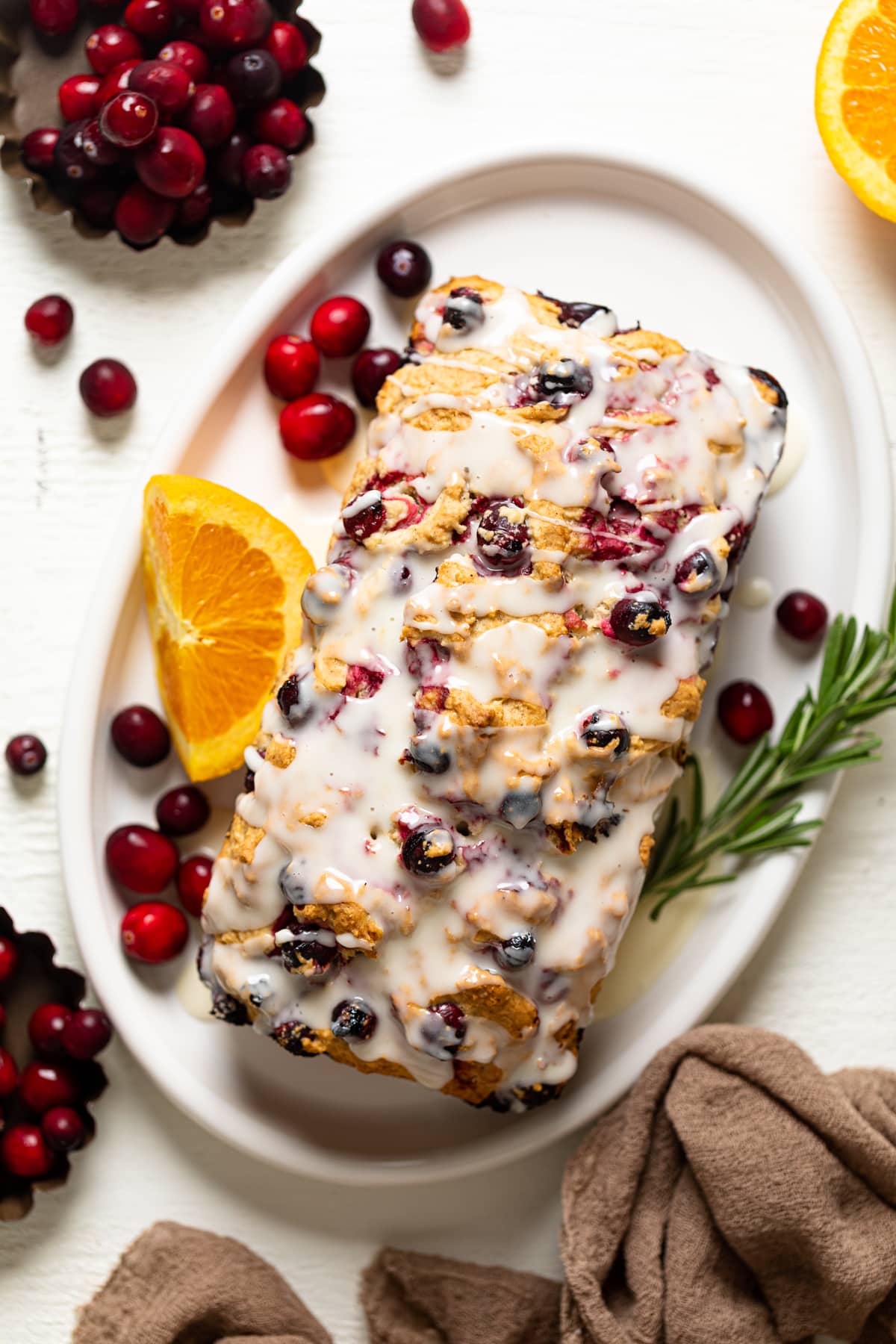 Loaf of Vegan Orange Cranberry Bread drizzled with orange glaze and on a plate