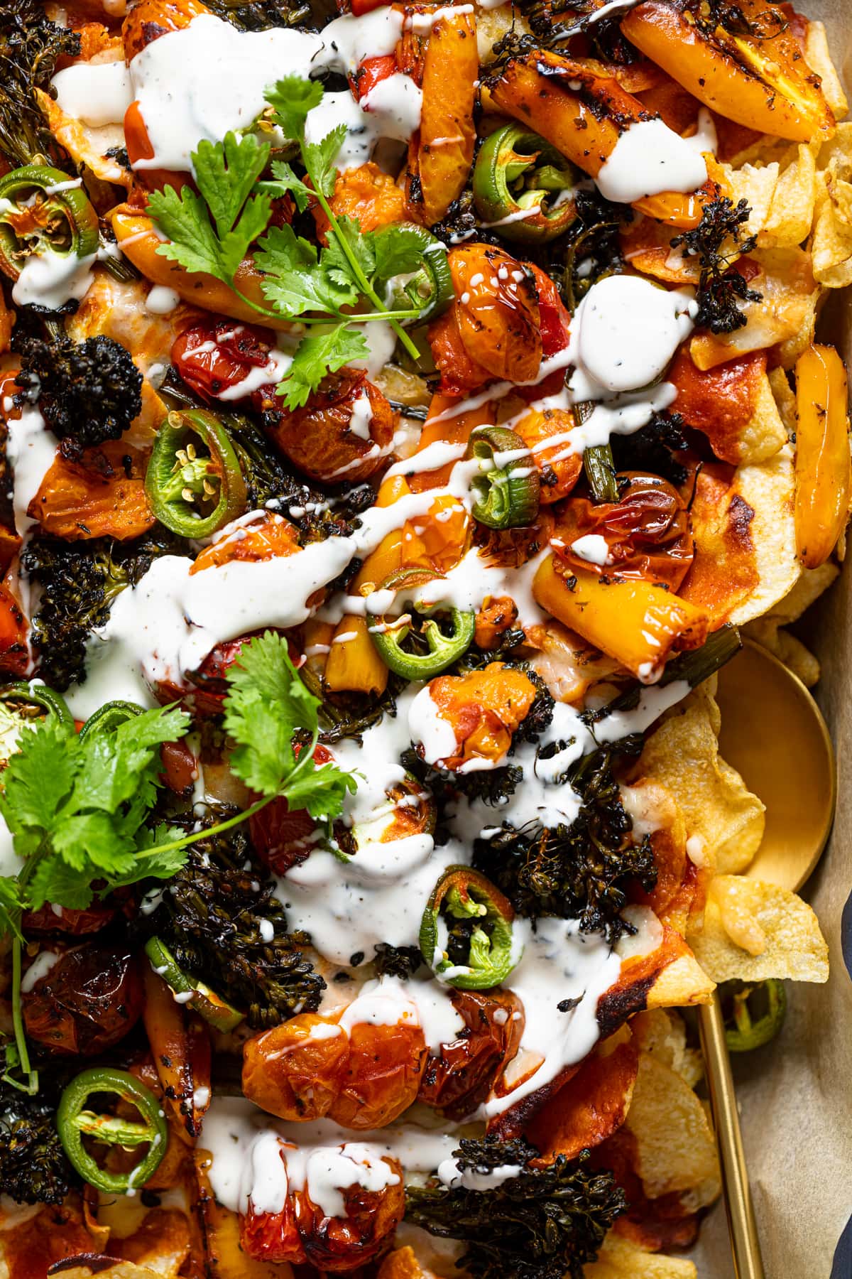 Sheet pan of Meatless Ranch Kettle Chip Nachos drizzled with ranch sauce