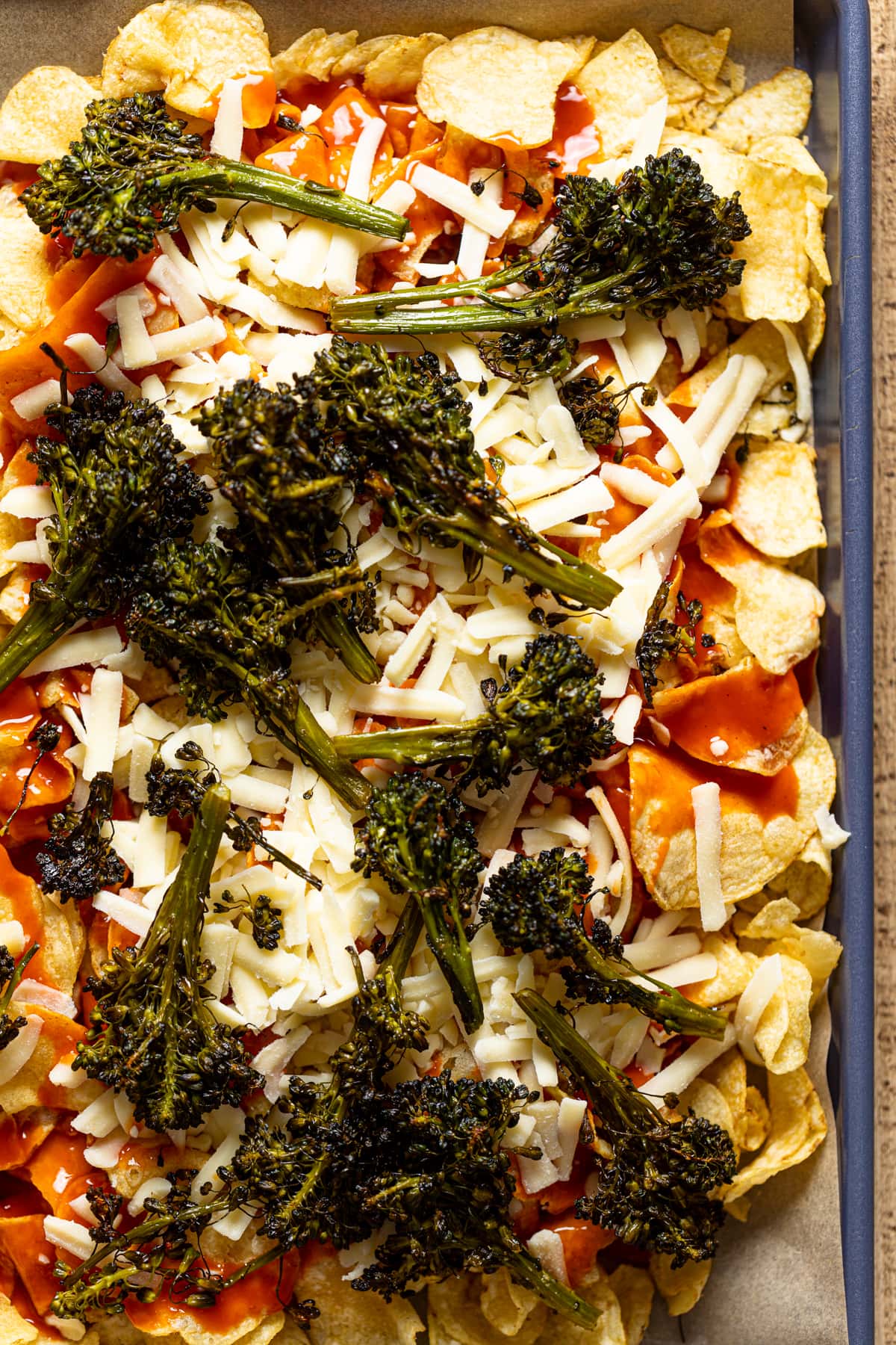 Kettle chips topped with red sauce, shredded cheese, and roasted broccolini