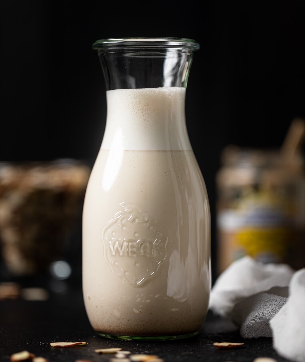 Free Photo  Milk carafe with bowl of almonds and bottle of milk high angle  view on a white wooden and piece of sack background