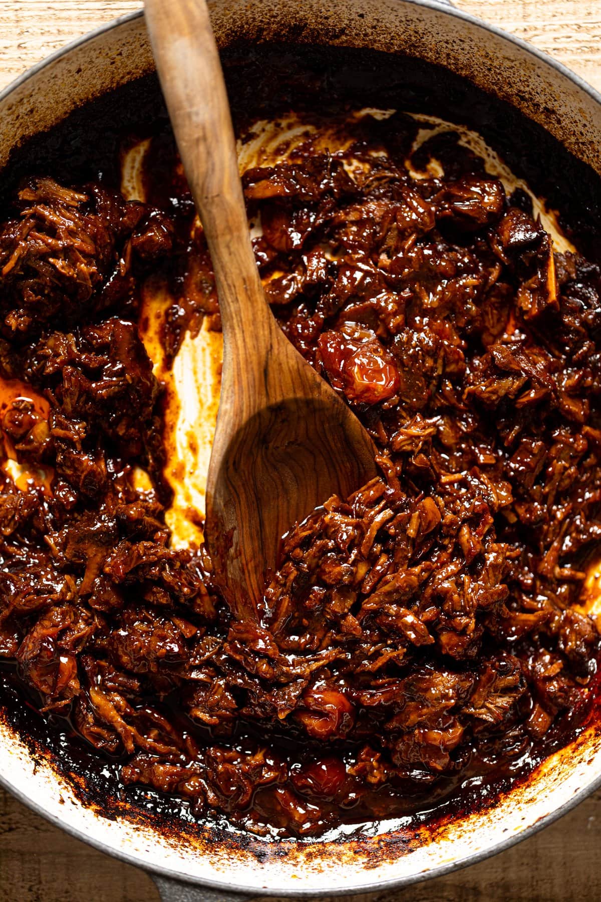 Closeup of a wooden spoon stirring Braised Steak Ragu