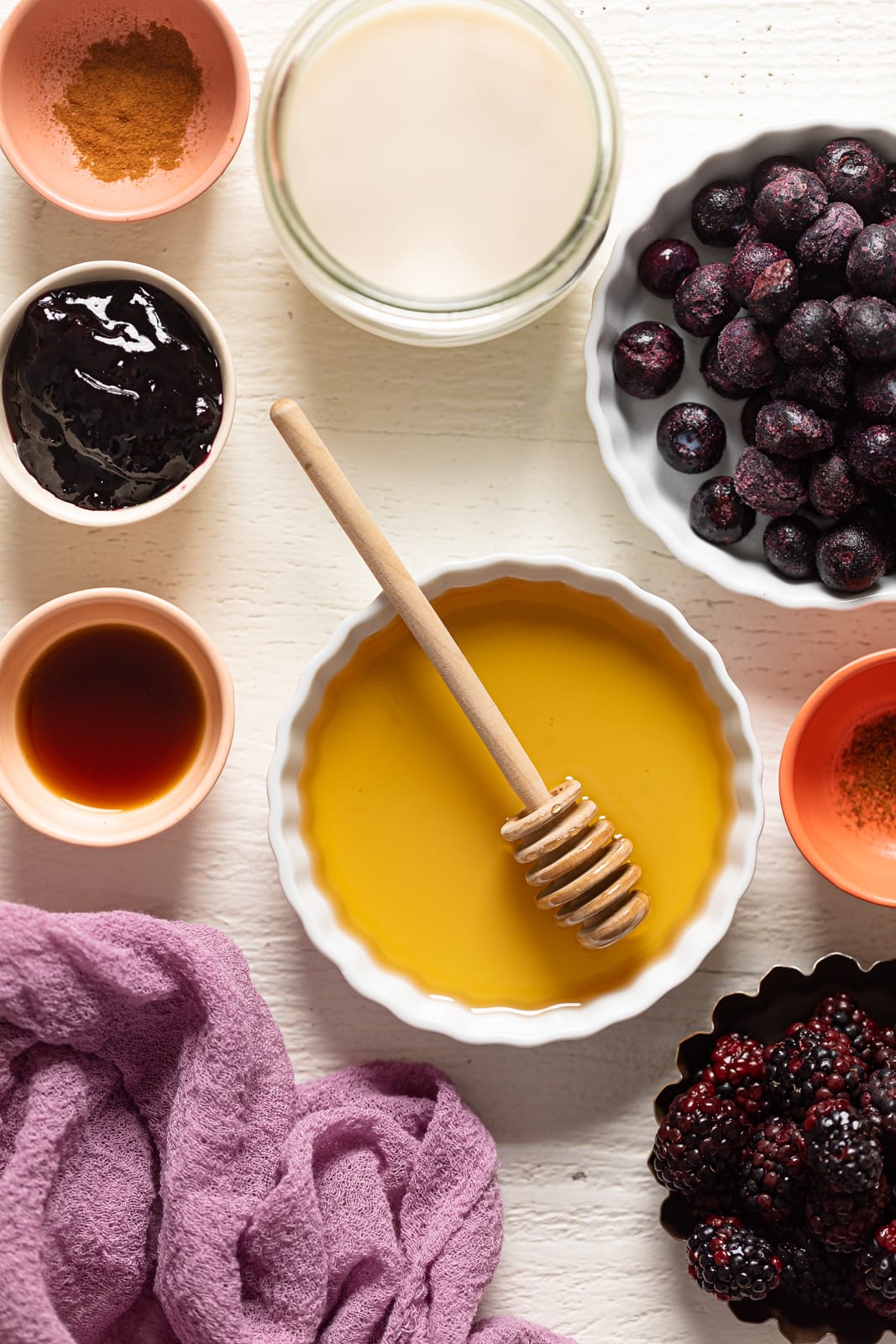 Ingredients for Blueberry Blackberry Jam Muffins including honey, blackberries, and frozen blueberries