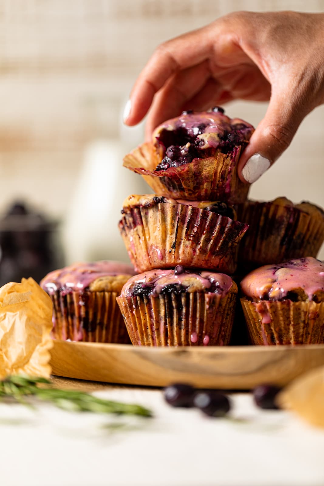 Hand grabbing a Blueberry Blackberry Jam Muffin from a pile
