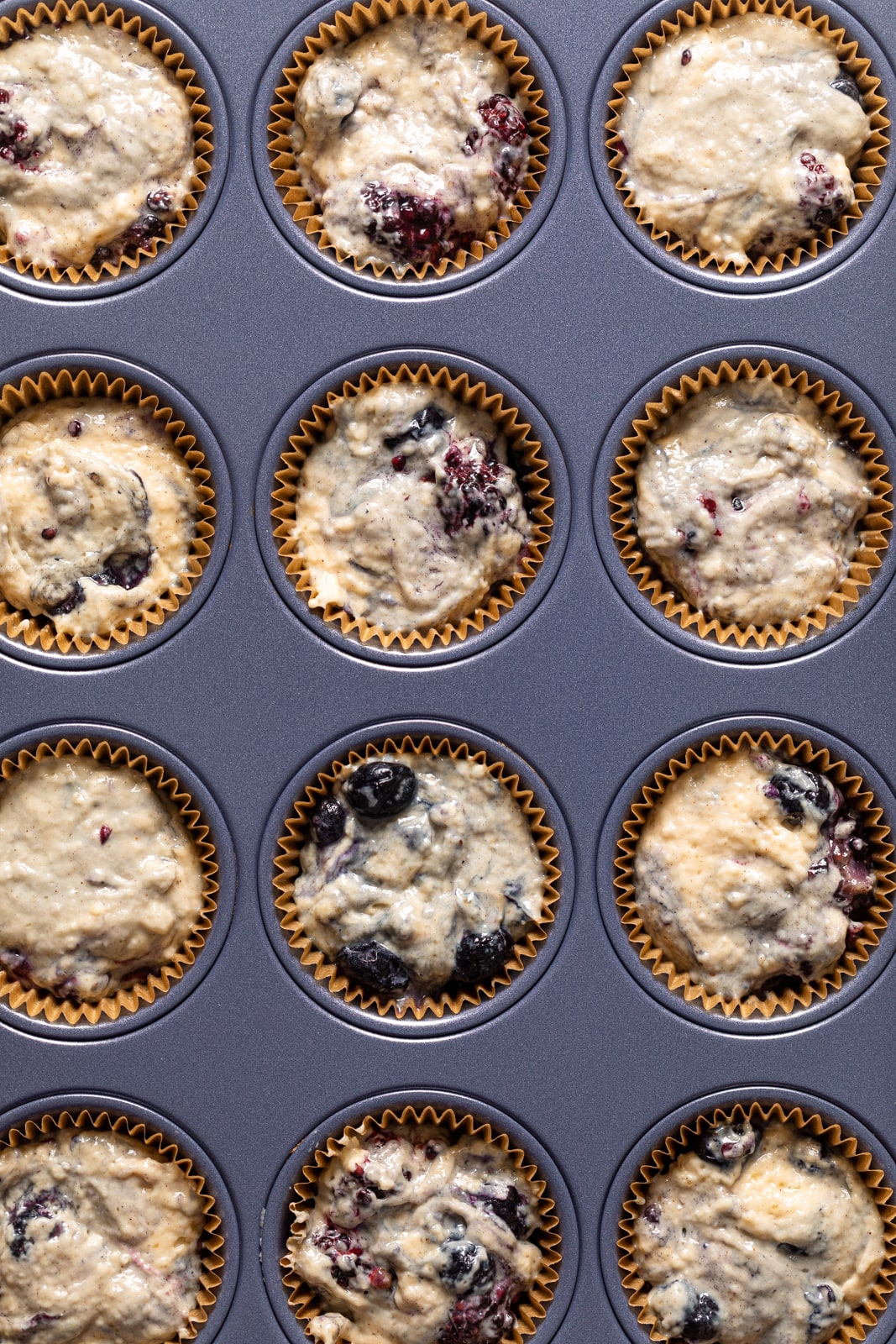 Muffin pan filled with Blueberry Blackberry Jam Muffin batter