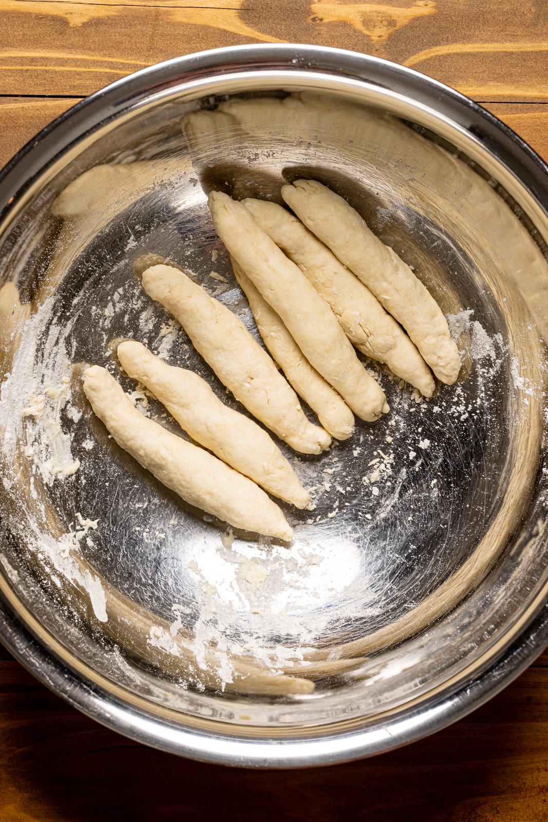 Dumplings in a silver bowl on a brown wood table.