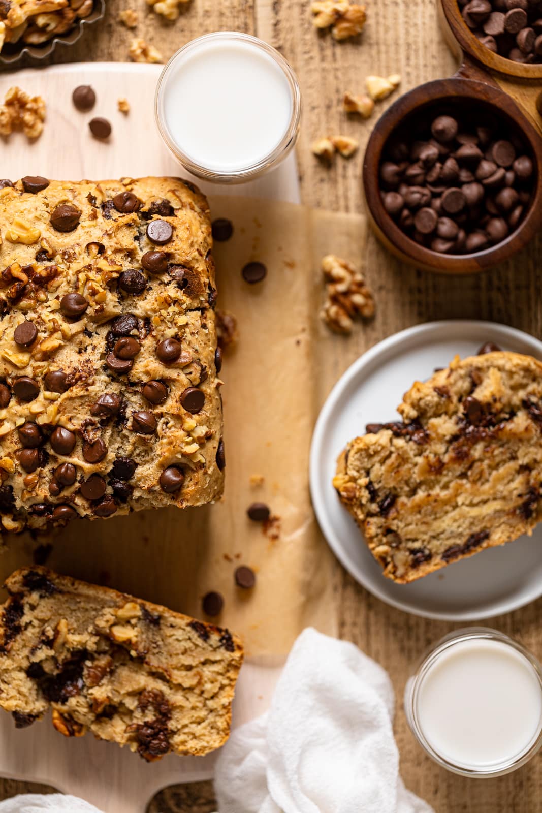 Overhead shot of Brown Butter Walnut Chocolate Chip Bread with some slices missing next to a small bowl of chocolate chips