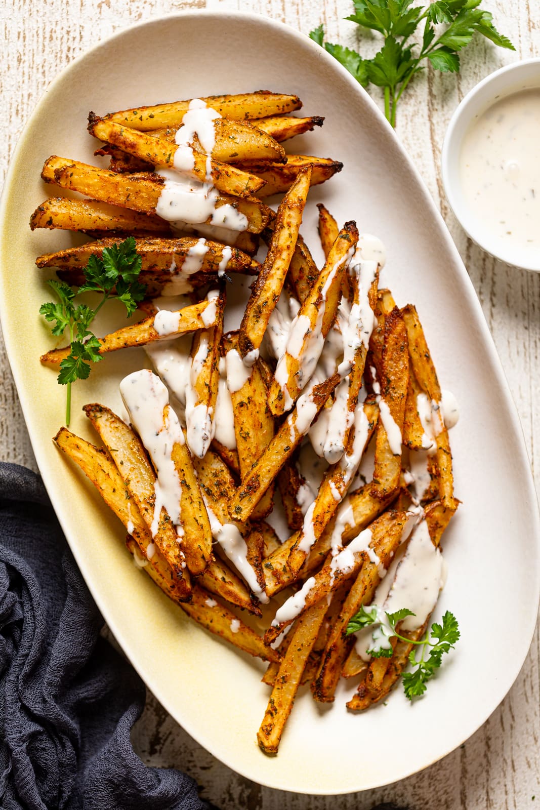 Overhead shot of a plate of Seasoned French Fries drizzled with ranch sauce