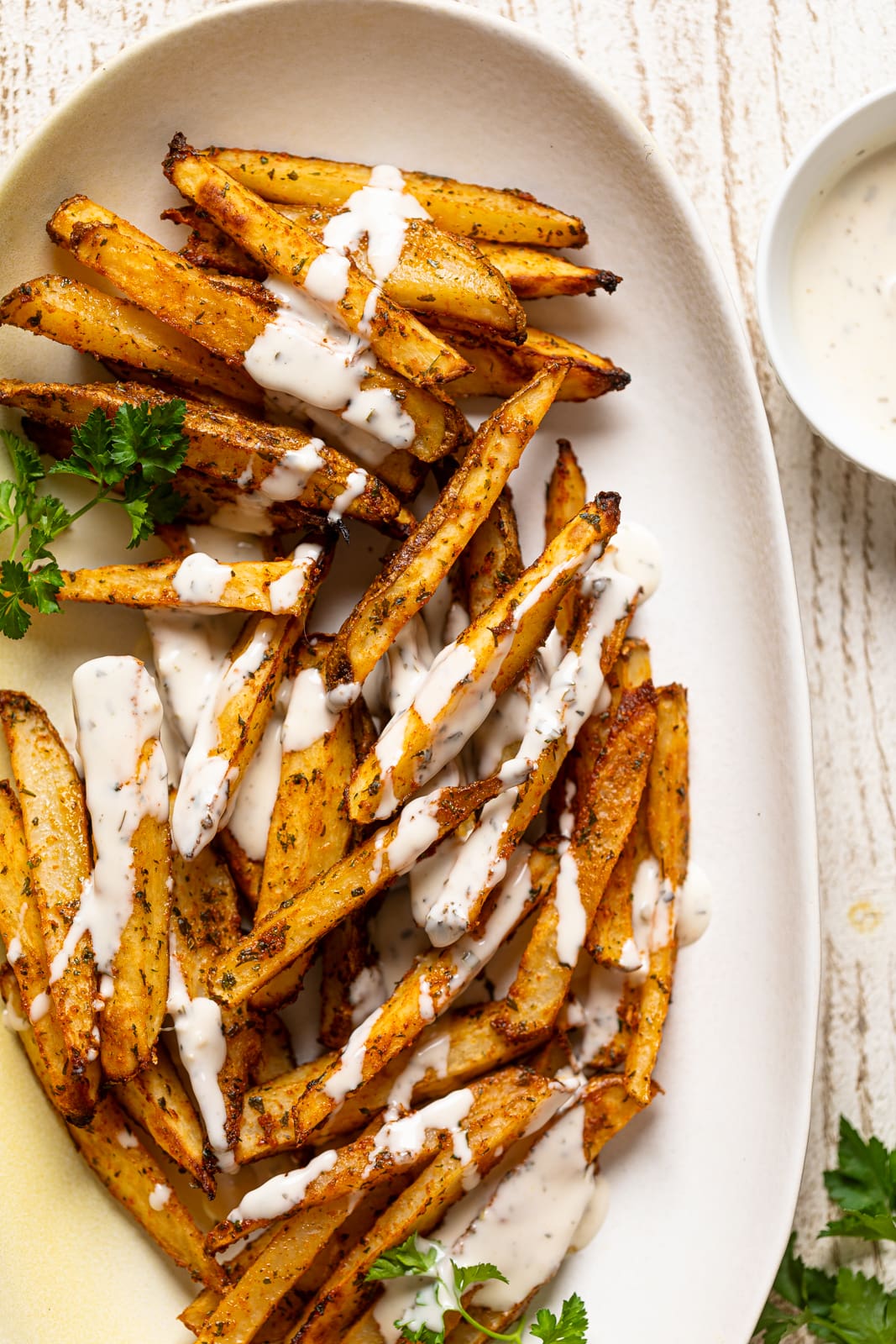Plate of Seasoned French Fries drizzled with ranch sauce
