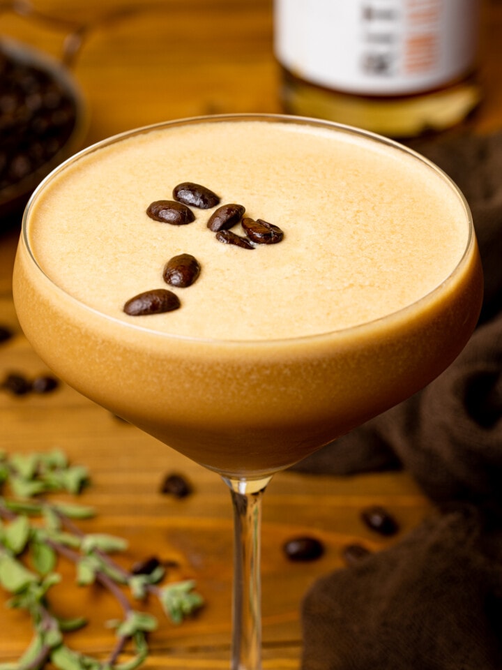 Up close shot of espresso martini in a glass topped with espresso coffee beans.
