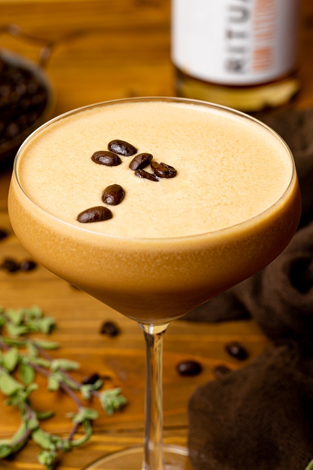 Up close shot of espresso martini in a glass topped with espresso coffee beans.