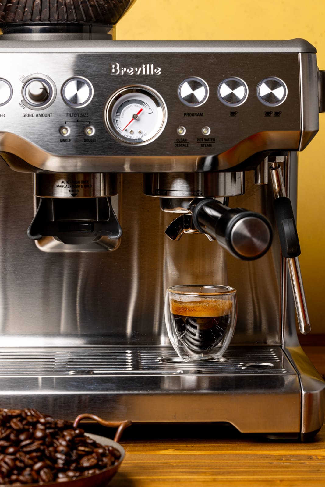 Espresso machine with cup and freshly-brewed espresso from coffee beans.