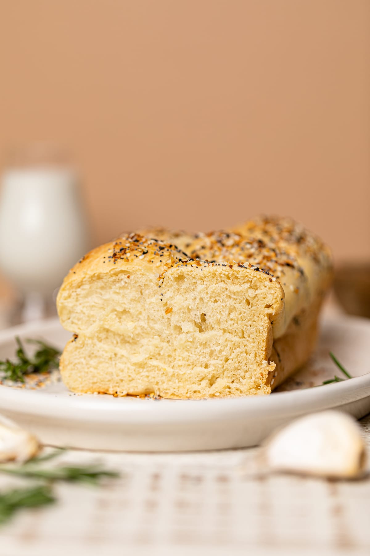 Loaf of Vegan Everything Bagel Brioche Bread with one end sliced off on a platter