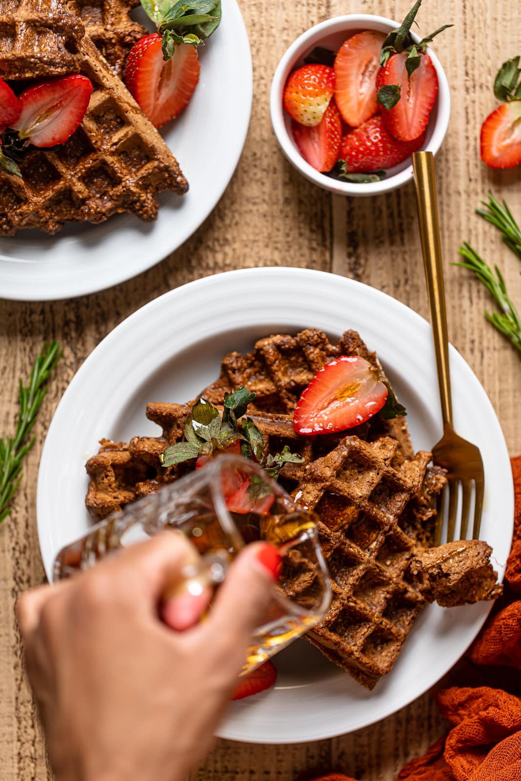 Hand pouring syrup onto Flourless Espresso Chocolate Waffles with Strawberries